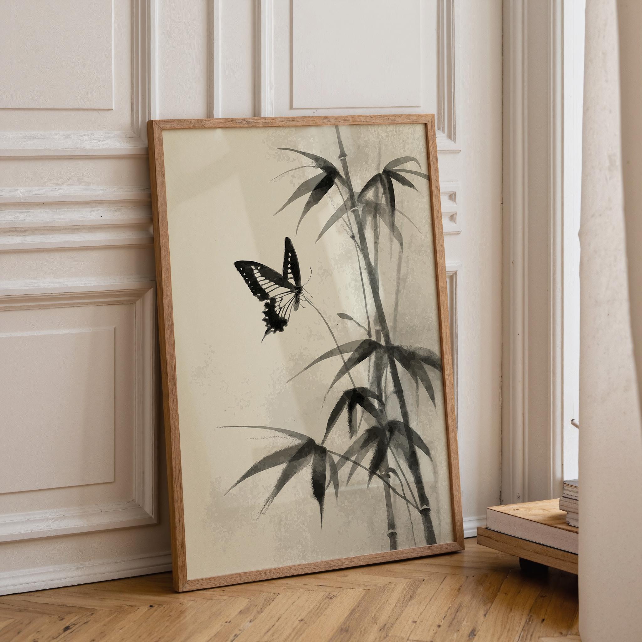 A framed art print featuring a black and white ink-style bamboo and butterfly design, leaning against a cream paneled wall on a light wood floor.