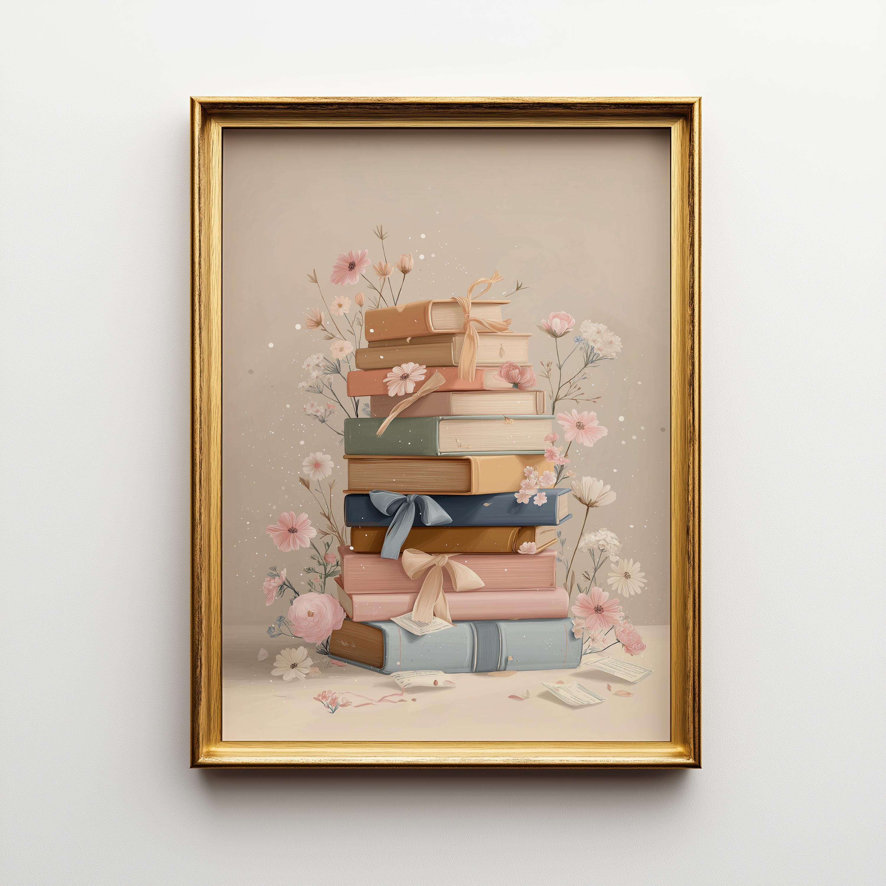 A framed art print featuring a stack of pastel-colored books adorned with pink flowers and ribbons, set in a gold frame against a light gray wall.