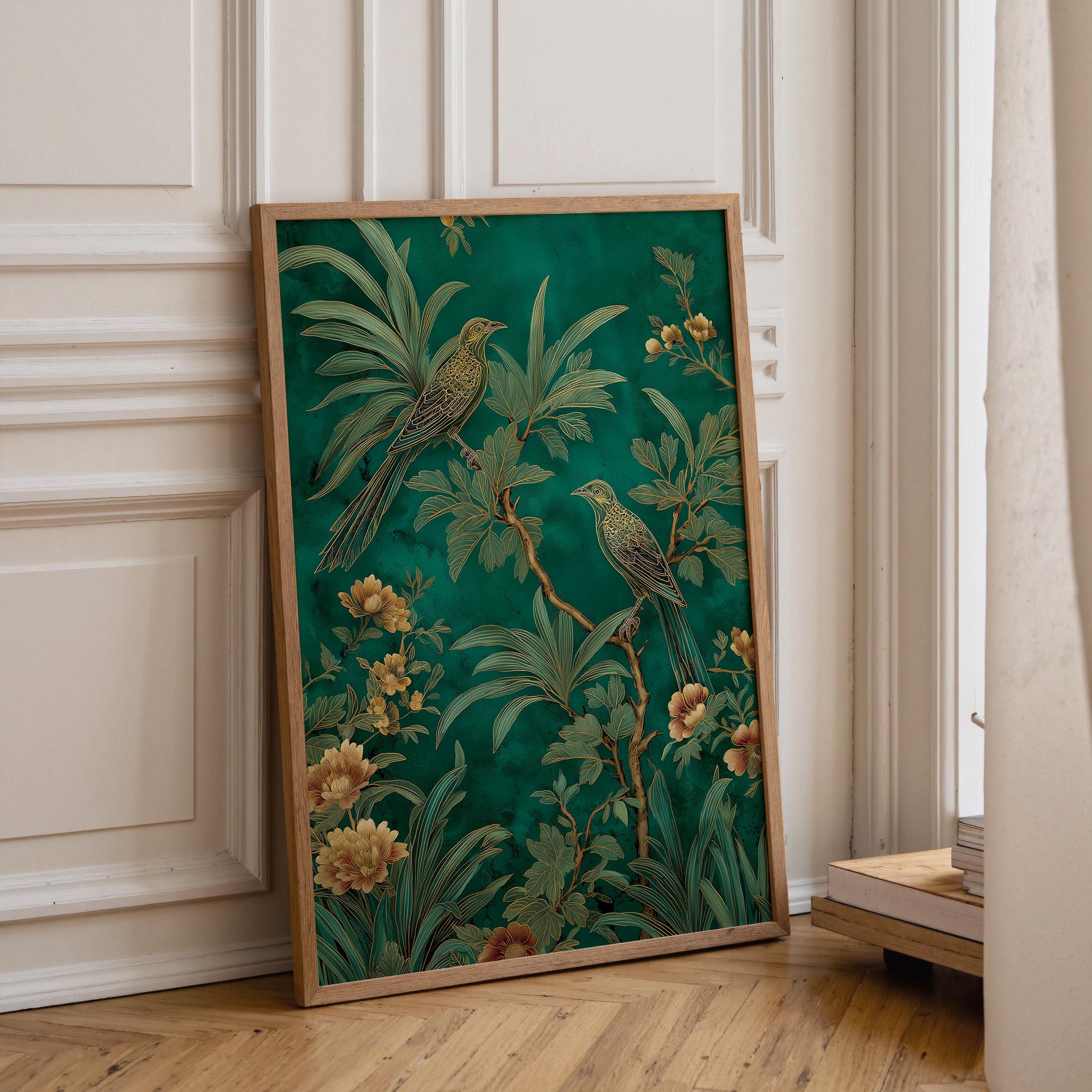 A framed botanical art print featuring two green birds perched among tropical leaves and flowers, leaning against a cream paneled wall on a light wood floor.